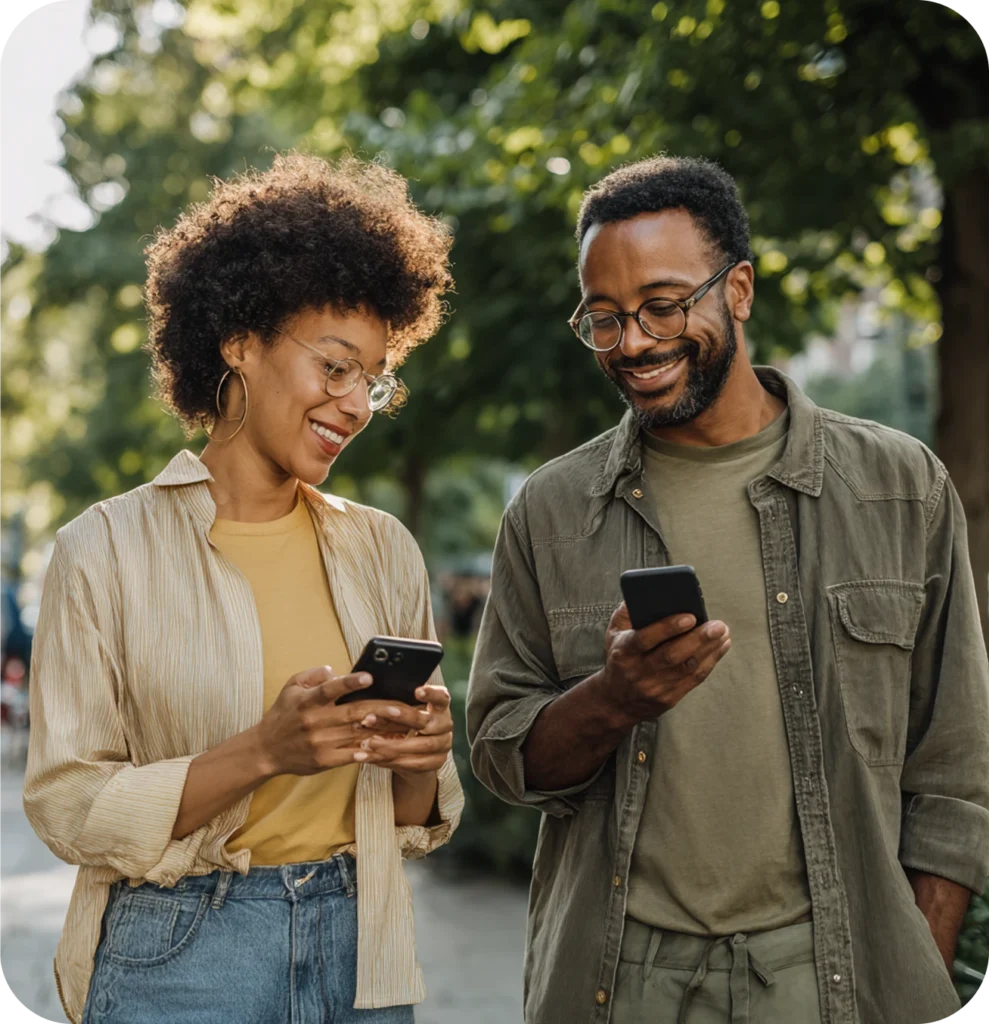 Duas pessoas em meio à natureza usando smartphones, representando conexão, sustentabilidade e tecnologia em energias renováveis